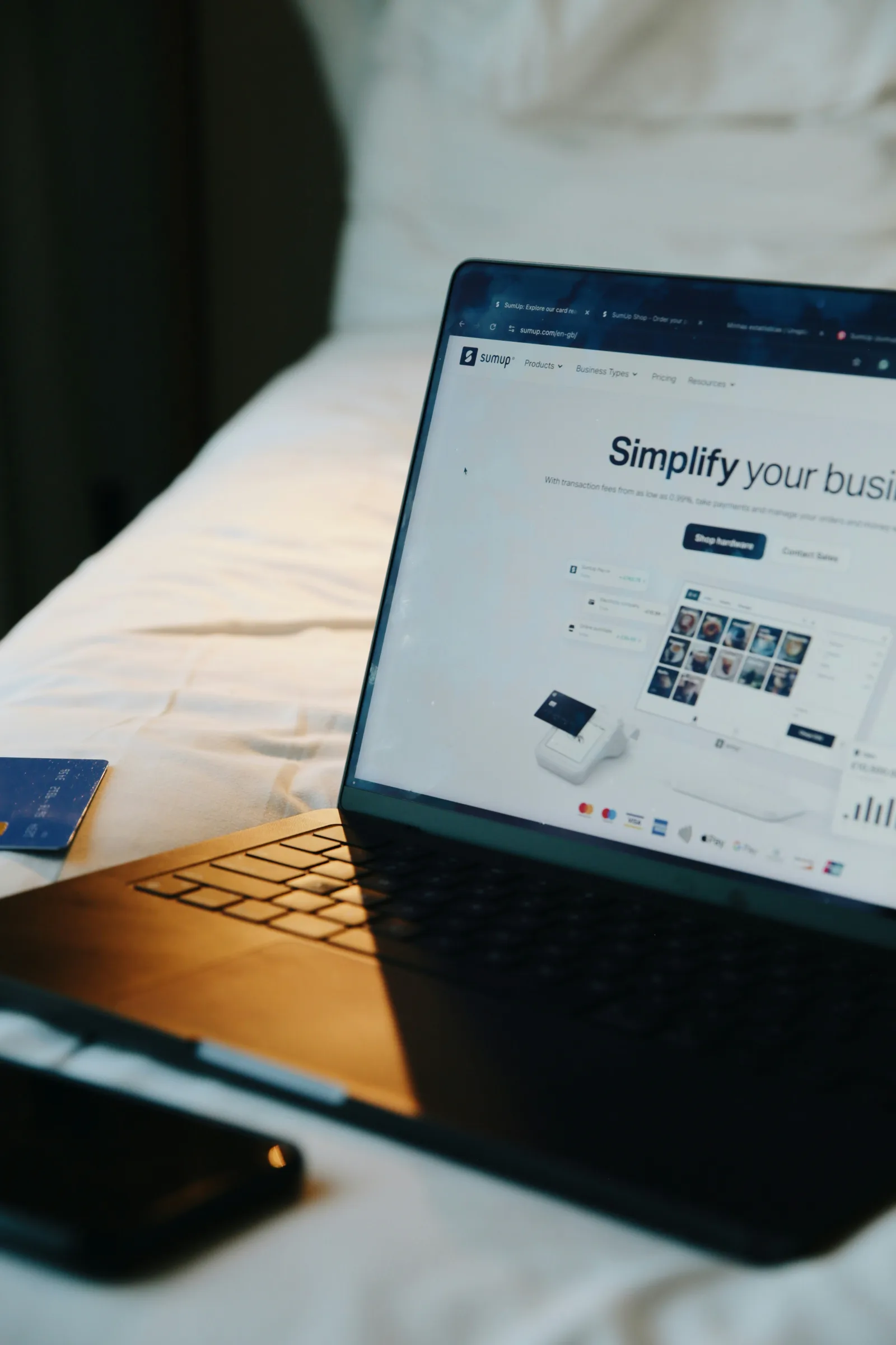Laptop hiển thị trang web doanh nghiệp trên giường, minh họa việc lên kế hoạch ngân sách website từ xa